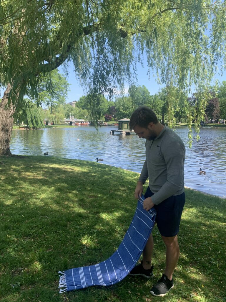Guy folding blanket at the Public Gardens in Boston during the summer