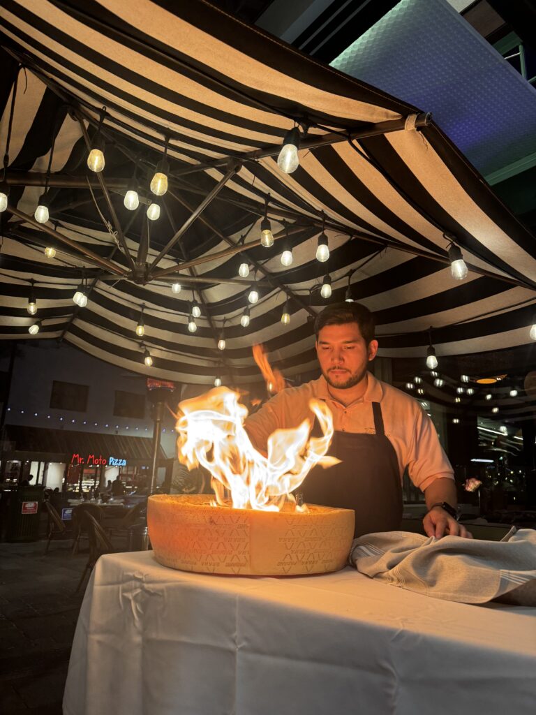 Guy cooking italian in parmesan wheel under a tent