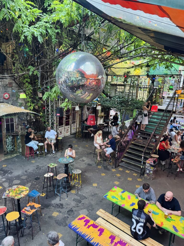 Patrons sitting under disco ball and hanging plants at Szimpla Kert