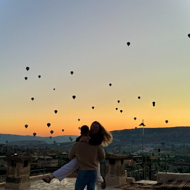 Couple on roof in front of hot air balloons in cappadocia