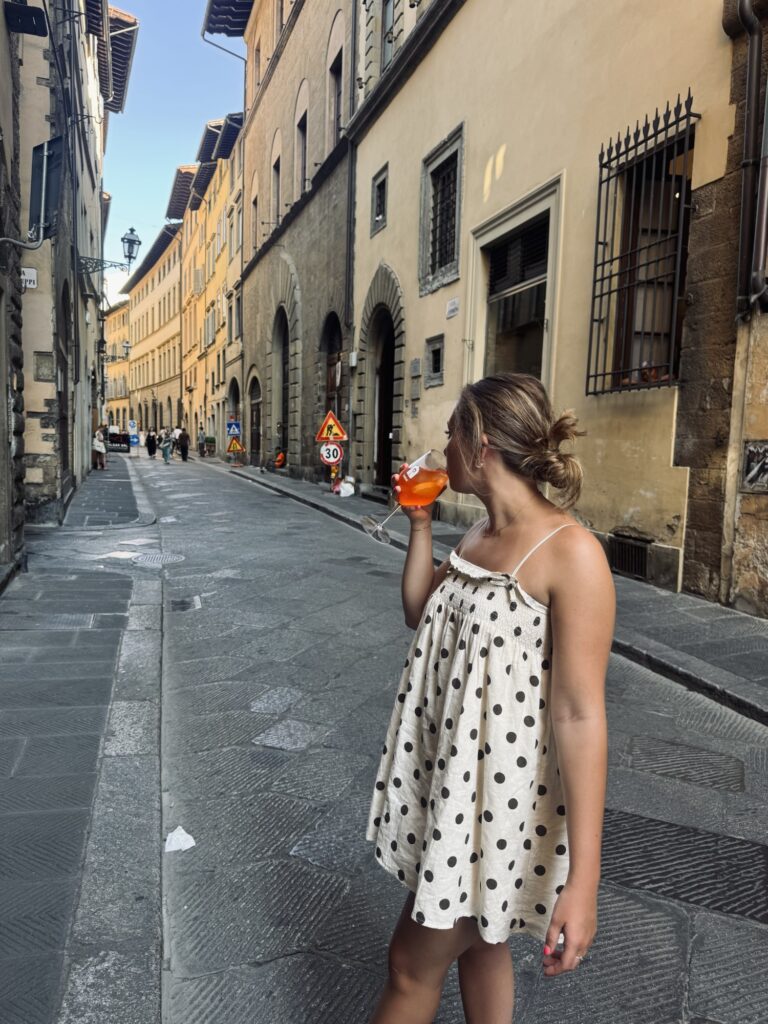Drinking an aperol spritz from a wine window in florence