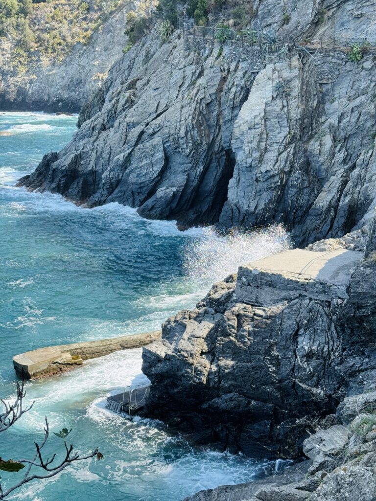 Waves crashing against large rocks in Cinque Terre